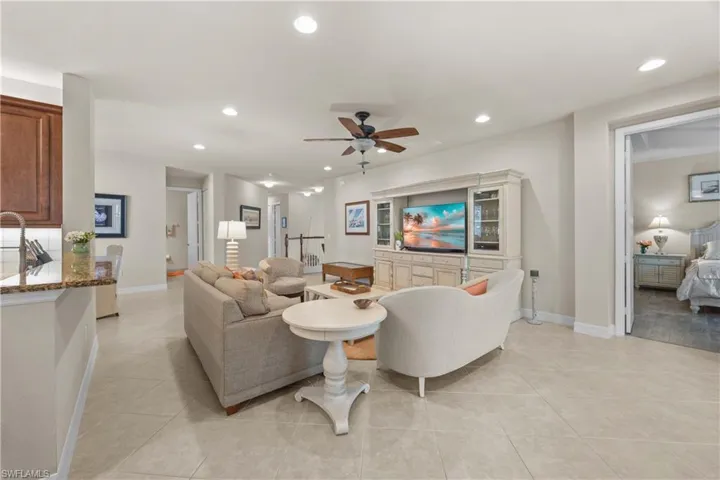 Living room with light tile patterned flooring, ceiling fan, and sink