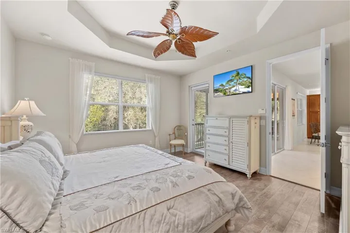 Bedroom featuring light wood-type flooring, ceiling fan, and a tray ceiling
