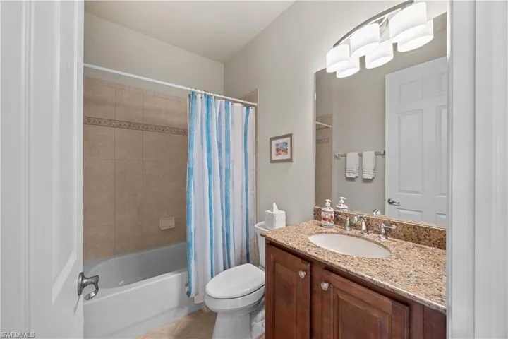 Full bathroom with vanity, toilet, tile patterned flooring, and shower / bath combo with shower curtain
