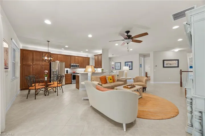 Living room with light tile patterned floors and ceiling fan with notable chandelier