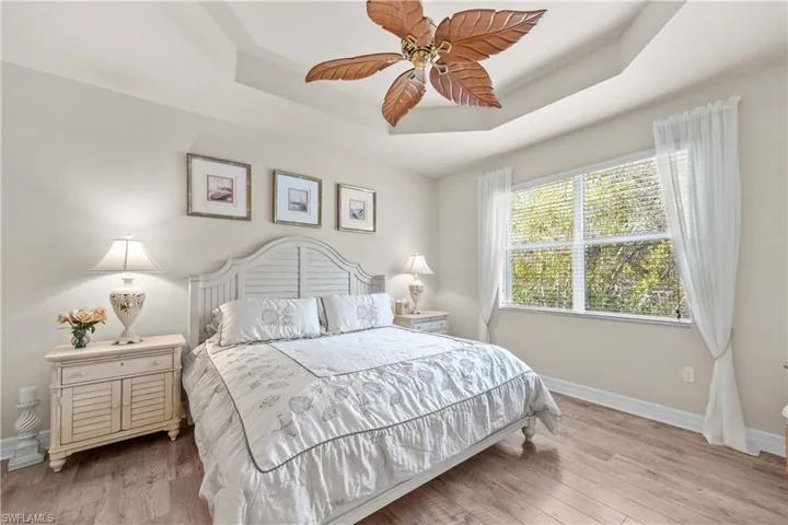 Bedroom featuring light hardwood / wood-style floors, a raised ceiling, and ceiling fan
