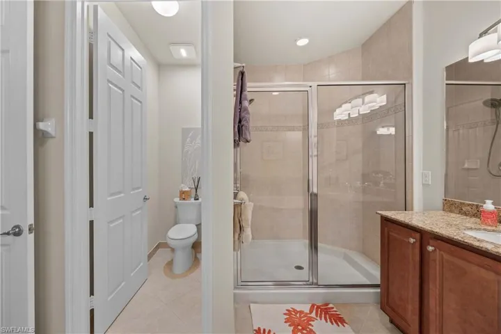Bathroom with vanity, a shower with shower door, tile patterned floors, and toilet