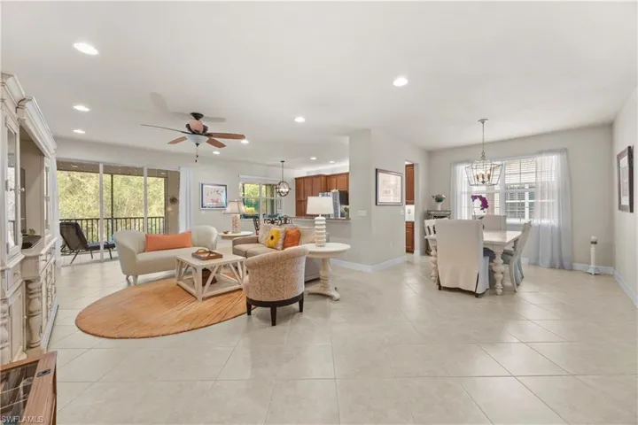 Living room featuring light tile patterned flooring and ceiling fan with notable chandelier