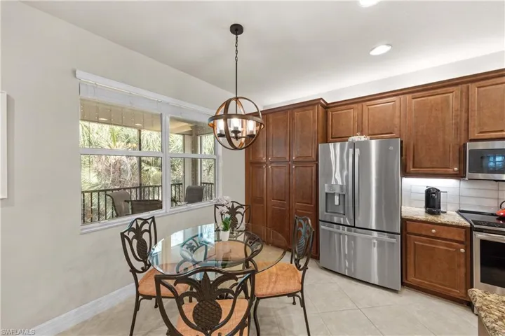 Kitchen featuring pendant lighting, light tile patterned floors, stainless steel appliances, light stone counters, and decorative backsplash