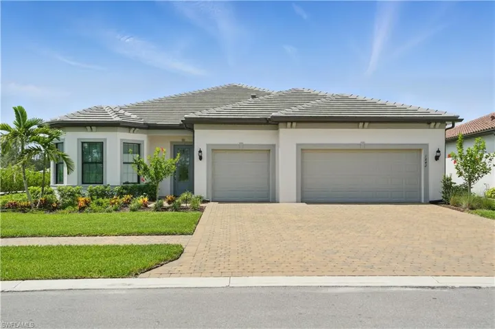 View of front facade featuring a garage, decorative driveway, a front yard, a tile roof, and stucco siding