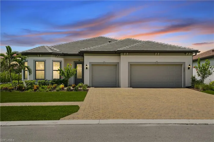 View of front of house with driveway, a garage, a front lawn, stucco siding, and a tiled roof