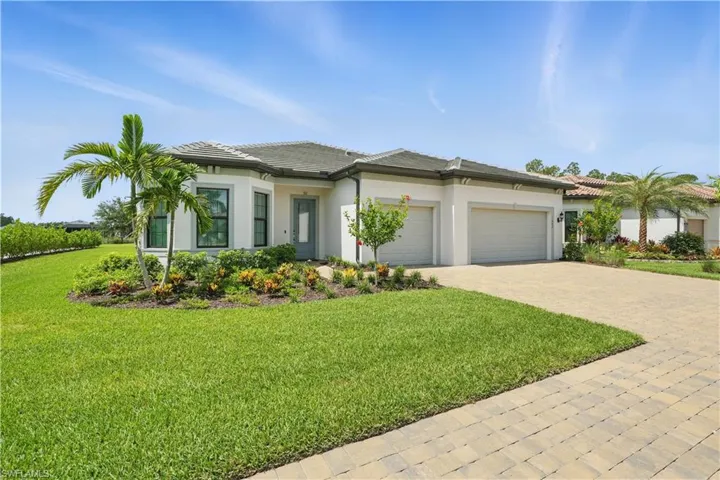 View of front of property with an attached garage, decorative driveway, a front yard, stucco siding, and a tiled roof