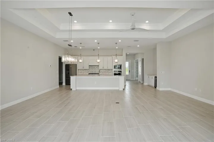 Unfurnished living room with crown molding, a tray ceiling, recessed lighting, and a ceiling fan