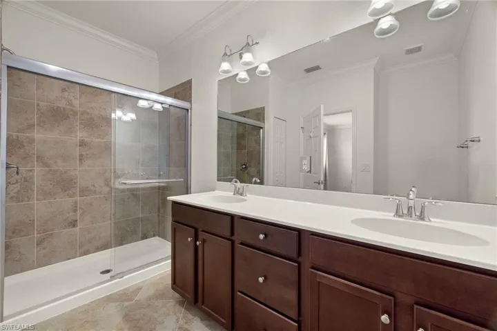 Bathroom with tile patterned floors, an enclosed shower, crown molding, and vanity