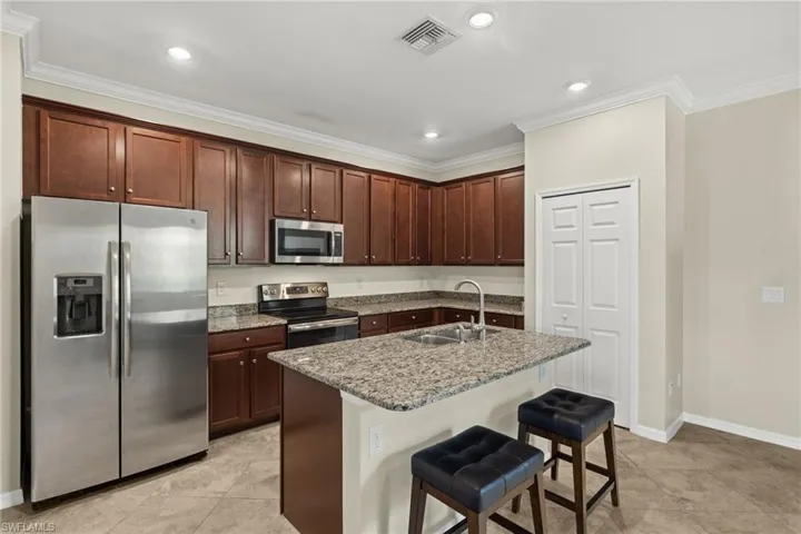 Kitchen featuring a kitchen breakfast bar, sink, appliances with stainless steel finishes, an island with sink, and light tile patterned floors