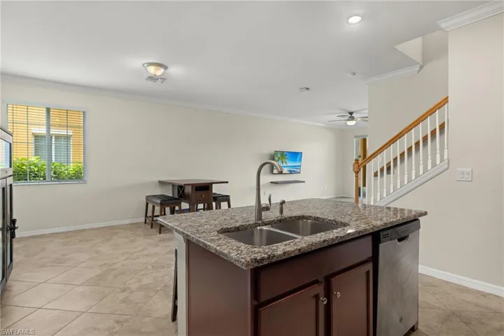 Kitchen featuring ceiling fan, stainless steel dishwasher, ornamental molding, light tile patterned floors, and sink