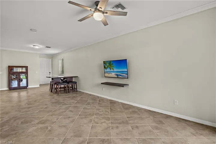 Tiled living room with ceiling fan and ornamental molding
