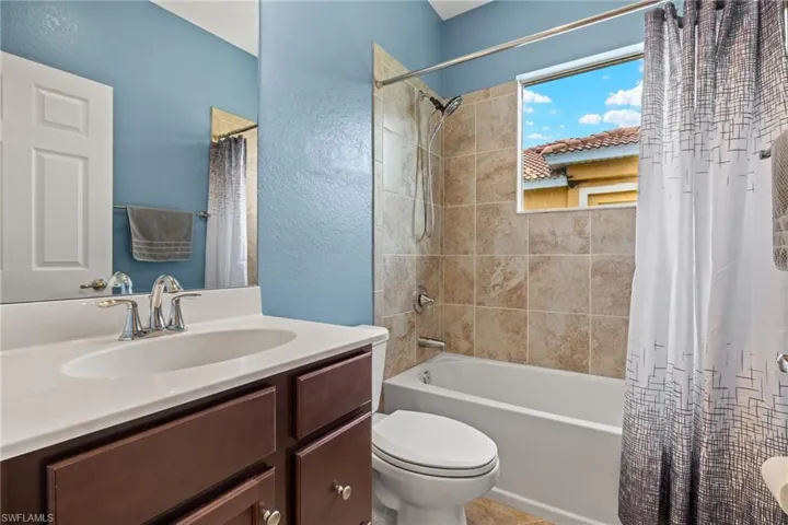 Full bathroom with toilet, shower / bathtub combination with curtain, and vanity