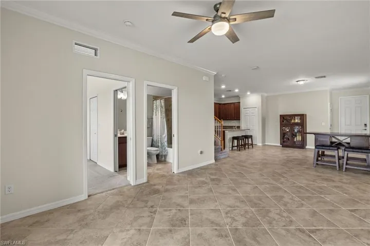 Unfurnished living room with ceiling fan, light tile patterned floors, and ornamental molding