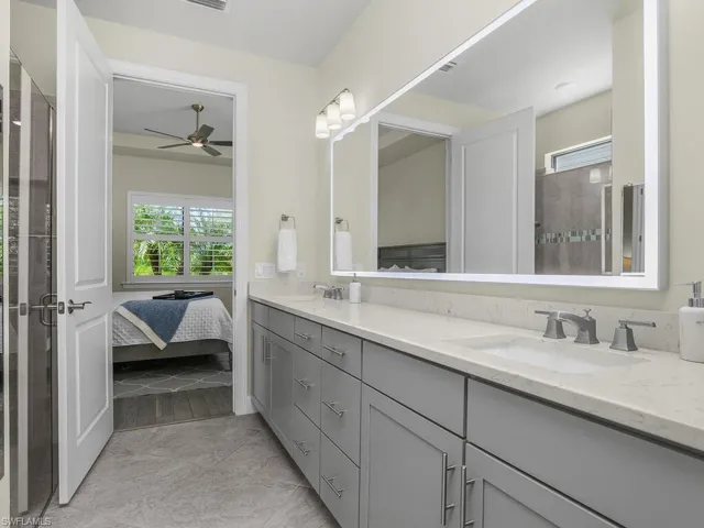 Owner Bath with tile flooring on diagonal, dual sinks quartz counters and custom back-lit mirror.