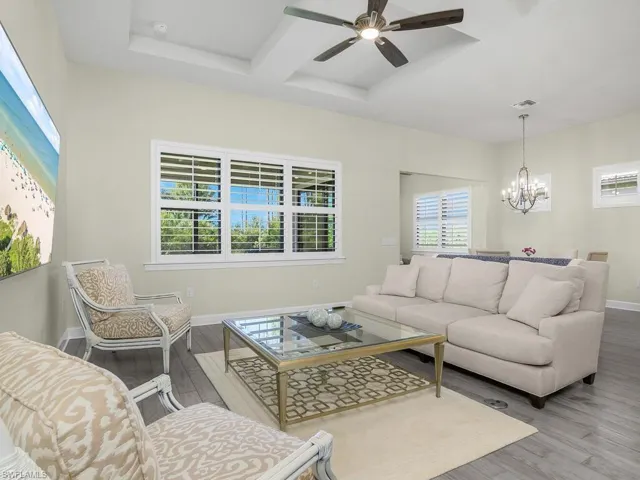 Open family room features plantation shutters, tray ceilings, and lots of natural light.