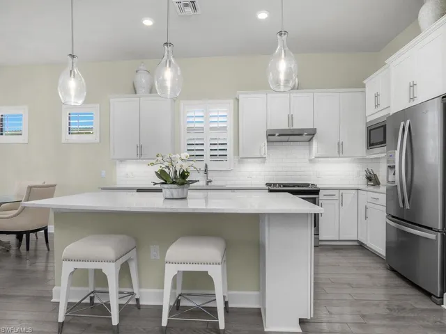 Plantation shutters, designer pendant lighting, and beveled subway tile give this kitchen a classic look.