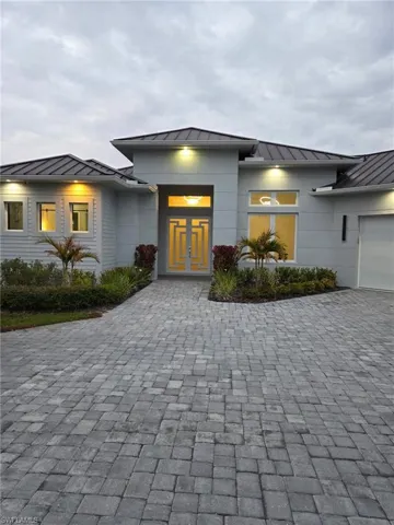 Entrance to property with a standing seam roof, an attached garage, and decorative driveway
