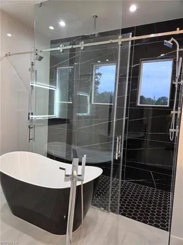 Full bath featuring a soaking tub, a shower stall, and tile walls