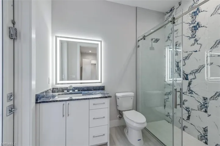 Bathroom with vanity and a marble finish shower