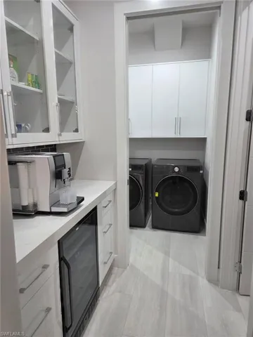 Laundry area featuring beverage cooler, washing machine and dryer, and cabinet space