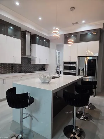 Kitchen with a kitchen bar, a kitchen island with sink, glass insert cabinets, and crown molding