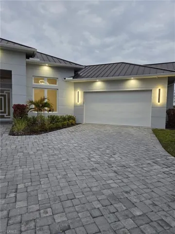 View of front of house featuring a standing seam roof, decorative driveway, and a garage