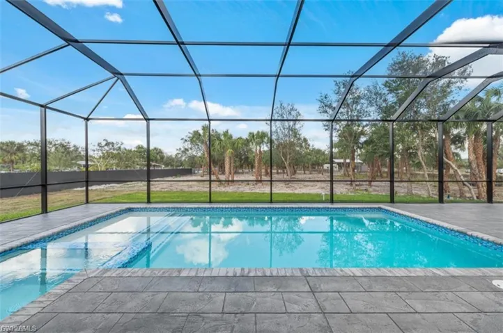 Swimming pool featuring a sunroom, a lawn, and glass enclosure