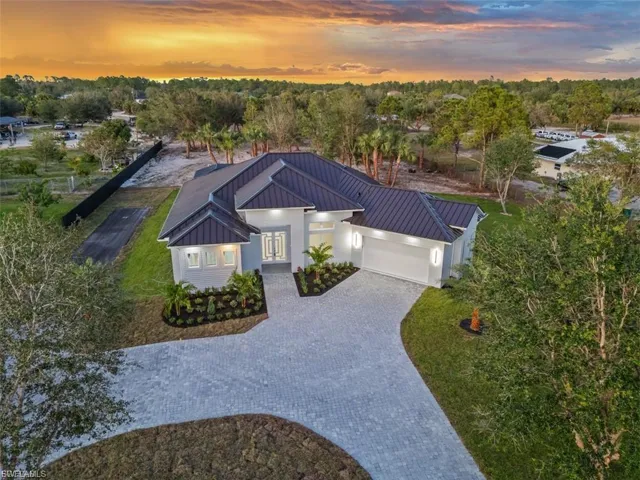 View of front of home featuring an attached garage, a standing seam roof, decorative driveway, french doors, and view of wooded area