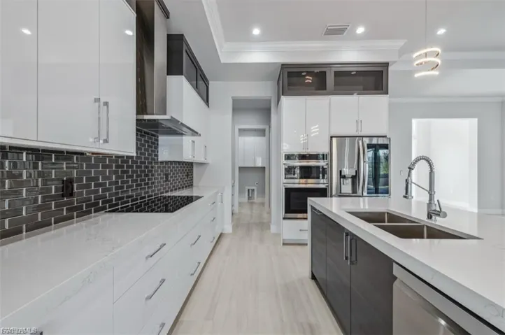 Kitchen featuring light stone countertops, hanging light fixtures, modern cabinets, stainless steel appliances, and two tone cabinetry