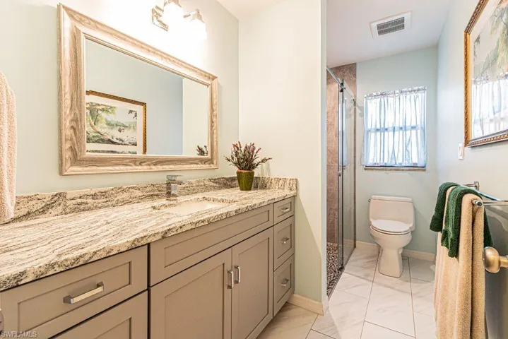 Bathroom featuring visible vents, toilet, a shower, vanity, and marble finish floor