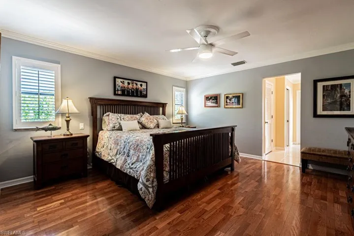 Bedroom with visible vents, baseboards, ornamental molding, and wood finished floors