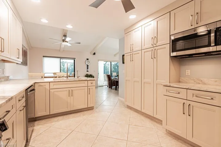 Kitchen featuring ceiling fan, a peninsula, appliances with stainless steel finishes, light tile patterned flooring, and a sink