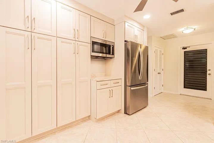 Kitchen with light tile patterned floors, a ceiling fan, visible vents, light countertops, and stainless steel appliances