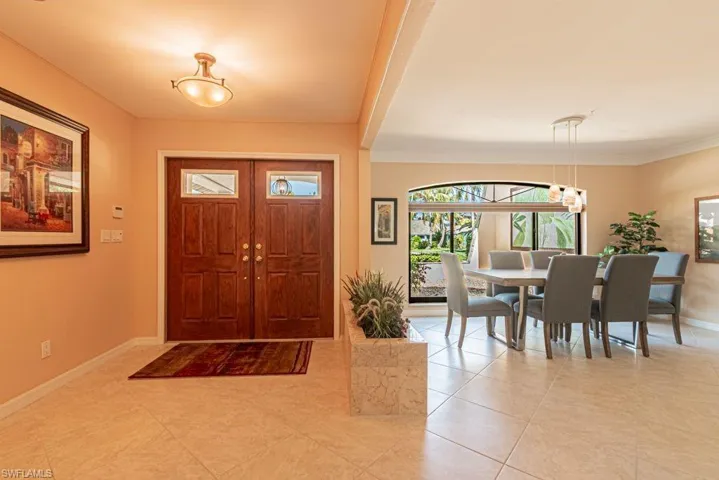 Foyer entrance featuring a notable chandelier, baseboards, crown molding, and light tile patterned flooring