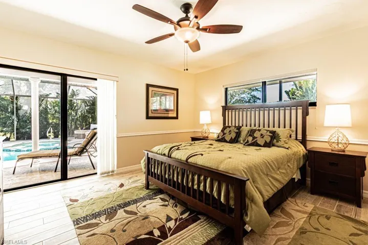 Bedroom featuring baseboards, access to outside, wood finished floors, and a ceiling fan