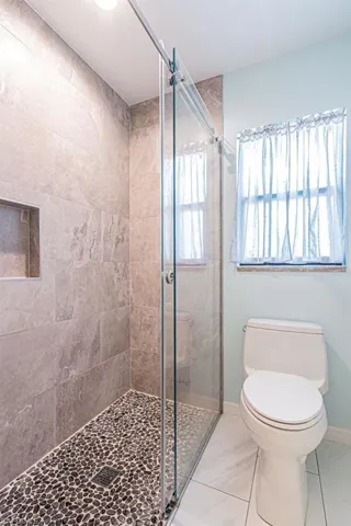 Full bathroom with toilet, a stall shower, and baseboards