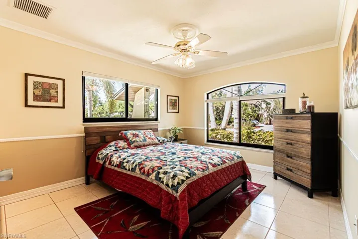 Bedroom with crown molding, ceiling fan, visible vents, light tile patterned flooring, and baseboards