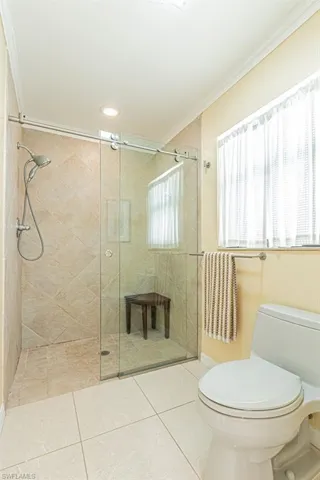Full bath featuring tile patterned flooring, a stall shower, ornamental molding, and toilet