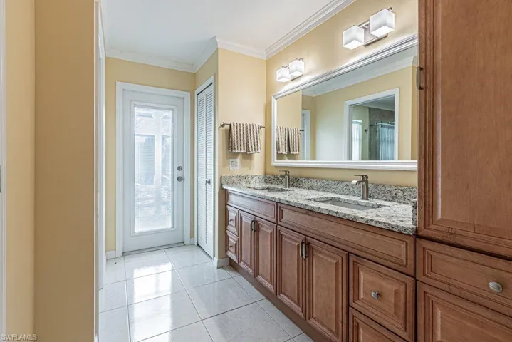Bathroom featuring tile patterned flooring, double vanity, a sink, and crown molding