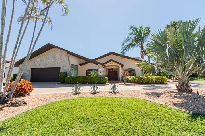 Ranch-style home featuring an attached garage, stone siding, concrete driveway, stucco siding, and a front lawn