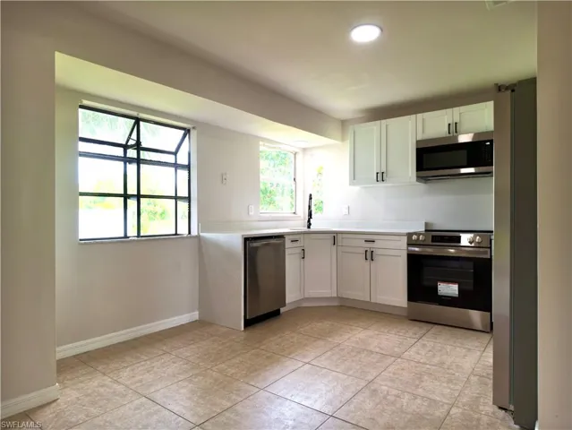 Modern kitchen featuring white shaker cabinetry, stainless steel appliances, light countertops, and tile flooring
