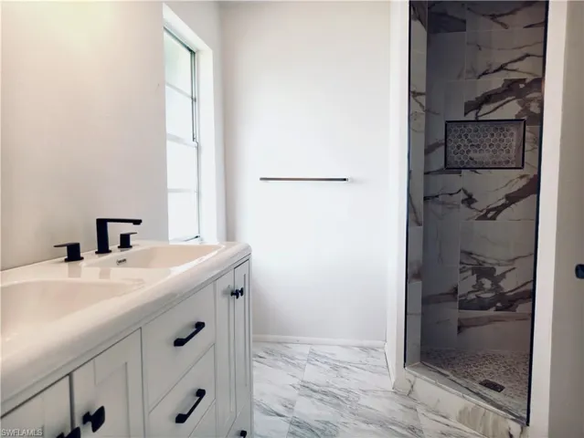 Double vanity with integrated sinks and matte black fixtures, set against light-colored walls