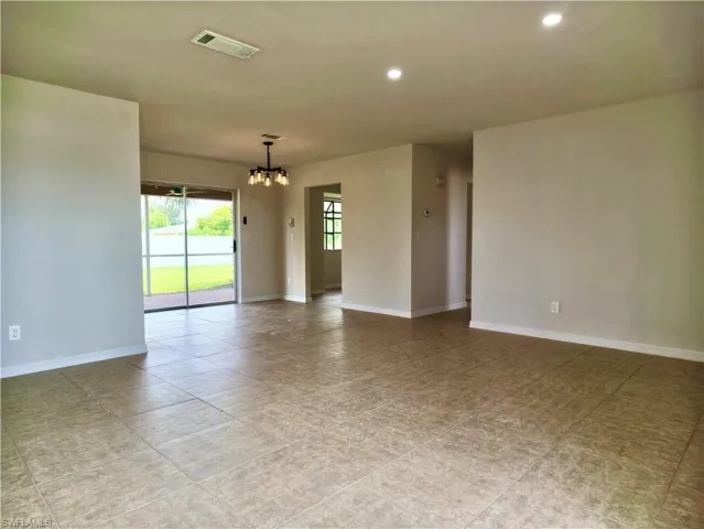 Spacious interior room with neutral-toned walls, tile flooring, and recessed lighting