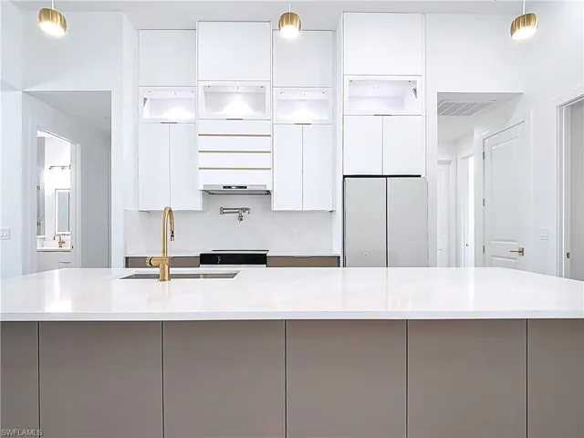 Kitchen with modern cabinets, white cabinetry, visible vents, light countertops, and a sink