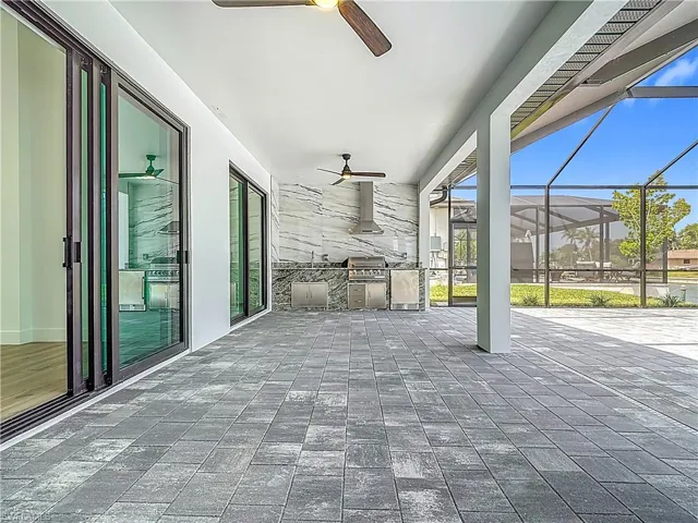 View of patio / terrace with a grill, a lanai, a ceiling fan, and an outdoor kitchen