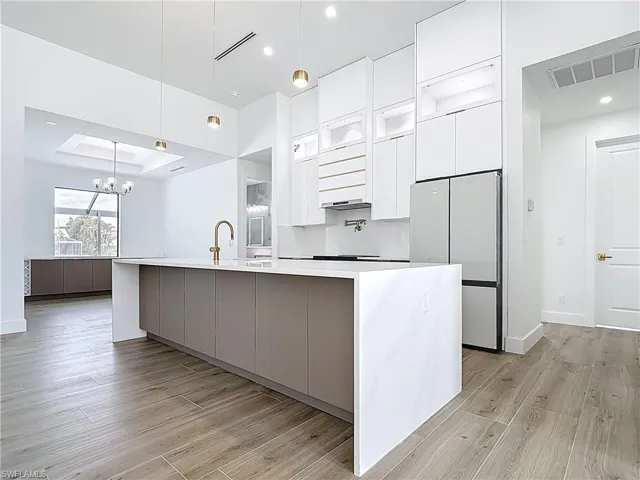 Kitchen featuring freestanding refrigerator, modern cabinets, white cabinets, visible vents, and a raised ceiling