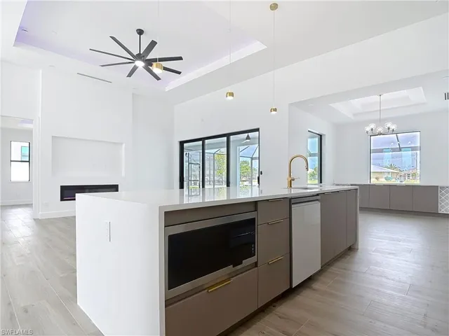Kitchen with modern cabinets, stainless steel microwave, white dishwasher, a raised ceiling, and open floor plan