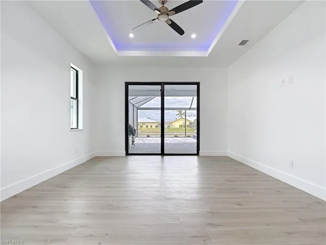 Empty room featuring visible vents, ceiling fan, a raised ceiling, and baseboards