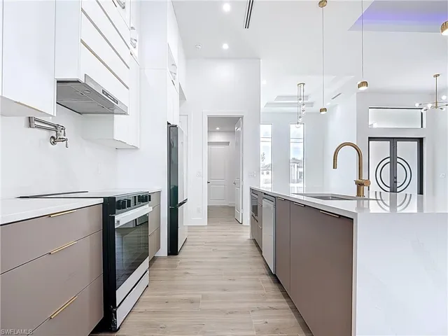 Kitchen featuring a sink, freestanding refrigerator, range with electric stovetop, and modern cabinets